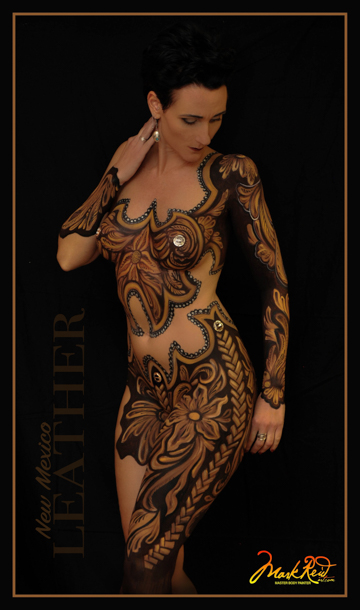 Woman painted with a very detailed gold and black body painting that resembles leather standing an looking down to the right